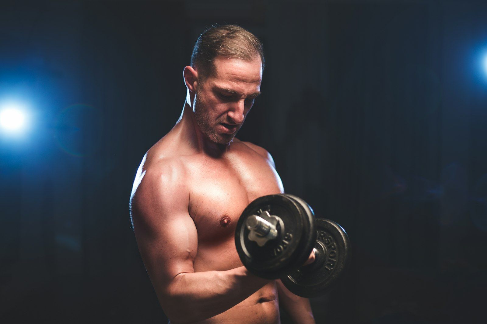 Een fitte man doet bicepscurls met twee dumbbells
